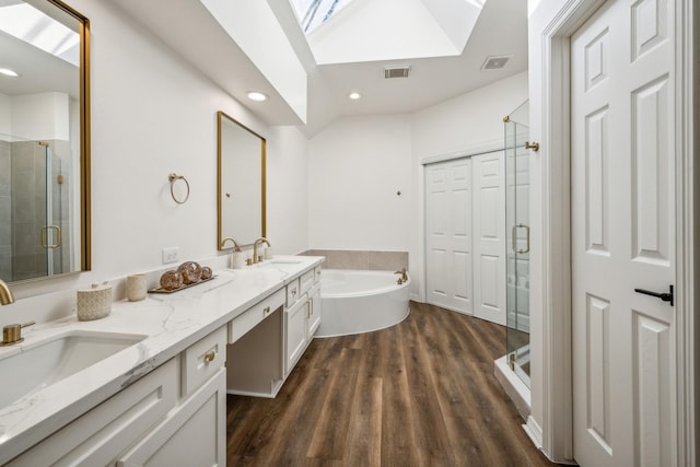 bathroom with lofted ceiling with skylight, independent shower and bath, hardwood / wood-style floors, and vanity