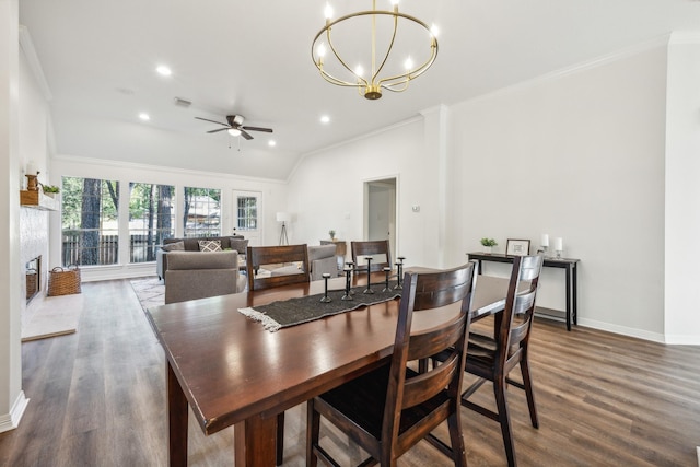 dining room featuring vaulted ceiling, dark wood-type flooring, ornamental molding, and ceiling fan with notable chandelier