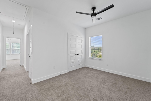 carpeted spare room featuring ceiling fan and plenty of natural light