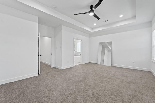 unfurnished bedroom featuring ceiling fan, a tray ceiling, ensuite bathroom, and carpet flooring