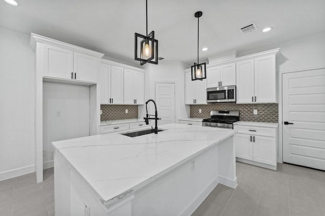 kitchen with pendant lighting, white cabinetry, stainless steel appliances, an island with sink, and sink