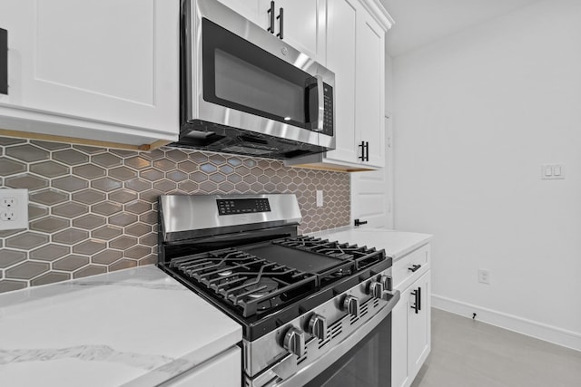 kitchen featuring light stone countertops, white cabinets, stainless steel appliances, and tasteful backsplash