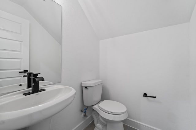 bathroom featuring toilet, lofted ceiling, and sink