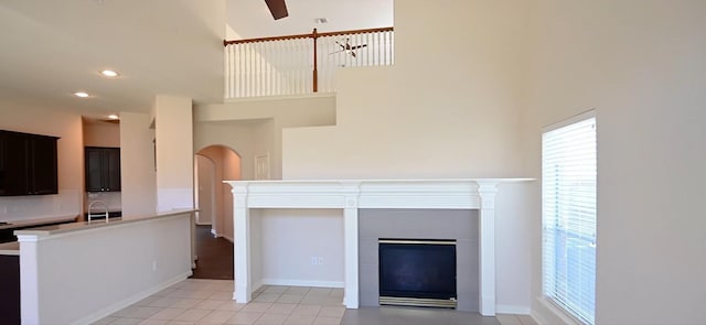 unfurnished living room with sink, light tile patterned floors, and a high ceiling