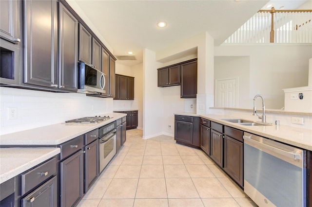 kitchen with sink, tasteful backsplash, dark brown cabinets, light tile patterned floors, and stainless steel appliances