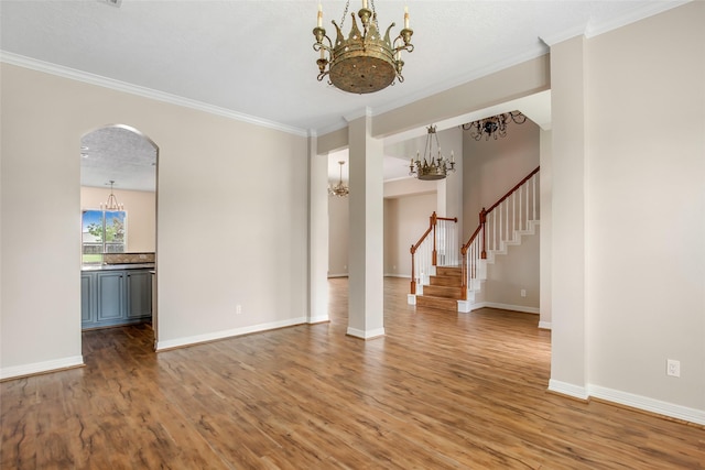 unfurnished living room featuring wood-type flooring, a notable chandelier, and crown molding