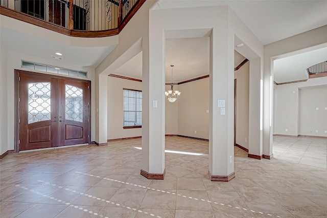 entrance foyer featuring an inviting chandelier, ornamental molding, a towering ceiling, and french doors