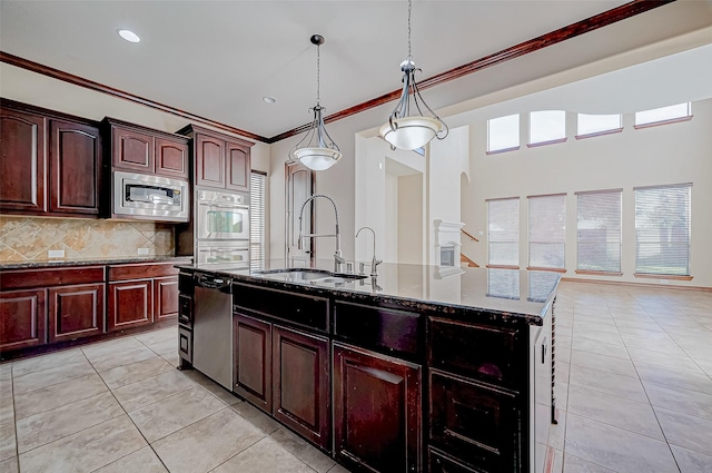 kitchen with appliances with stainless steel finishes, decorative light fixtures, sink, a kitchen island with sink, and crown molding