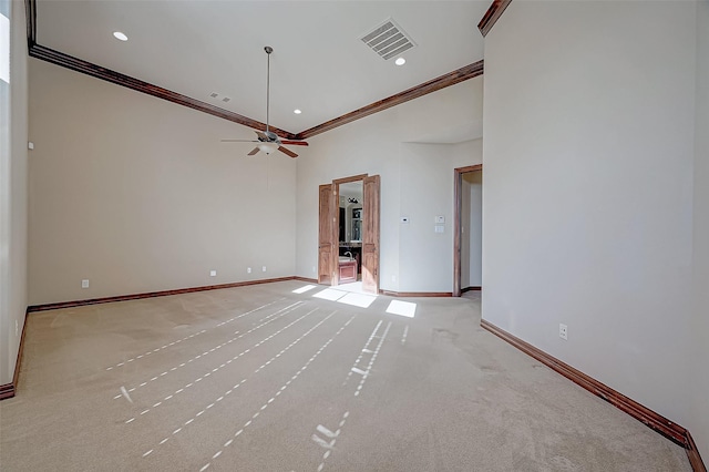 unfurnished living room with crown molding, light colored carpet, ceiling fan, and a high ceiling