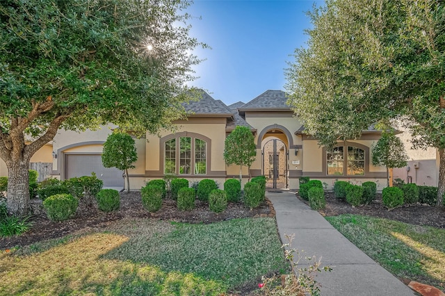 mediterranean / spanish-style house with french doors, a garage, and a front lawn