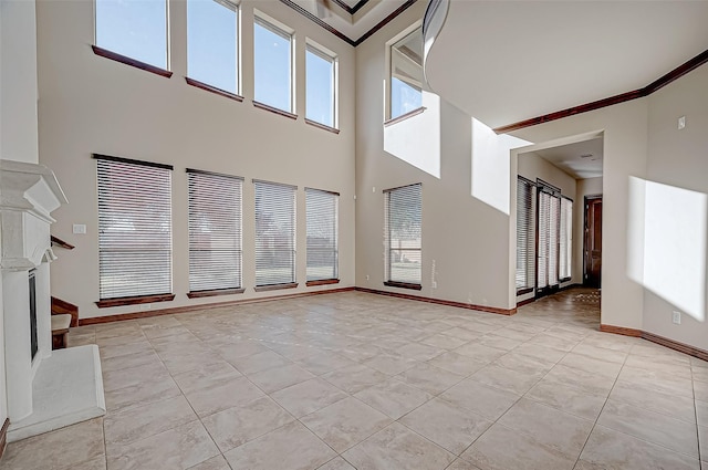 unfurnished living room with a high ceiling, ornamental molding, a healthy amount of sunlight, and light tile patterned floors