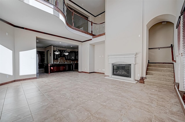 unfurnished living room with ornamental molding and a high ceiling