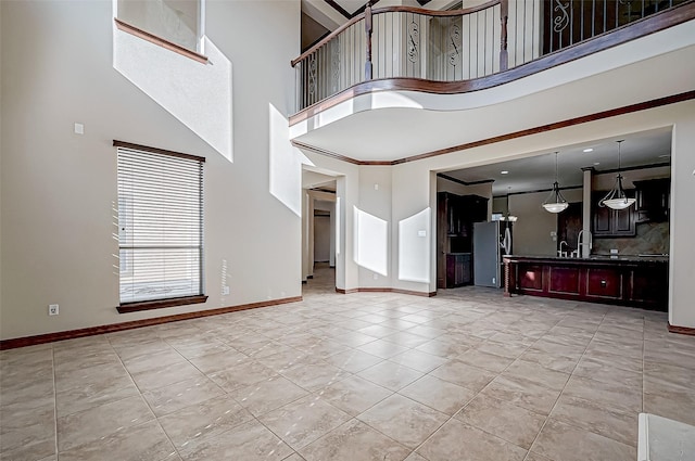 unfurnished living room featuring light tile patterned flooring, crown molding, and a high ceiling