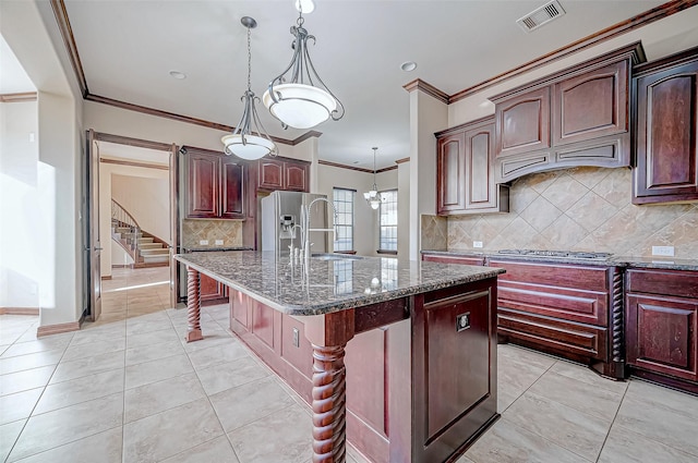 kitchen with a kitchen bar, sink, pendant lighting, dark stone counters, and a kitchen island with sink