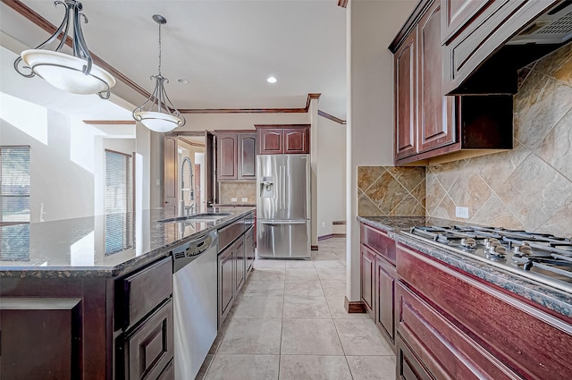 kitchen featuring sink, hanging light fixtures, appliances with stainless steel finishes, custom range hood, and dark stone counters