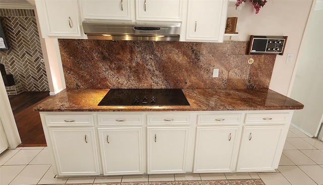 kitchen featuring exhaust hood, decorative backsplash, white cabinetry, light tile patterned floors, and black electric cooktop