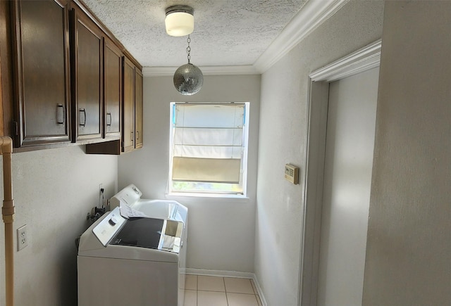 washroom featuring a textured ceiling, washer and clothes dryer, cabinets, ornamental molding, and light tile patterned floors