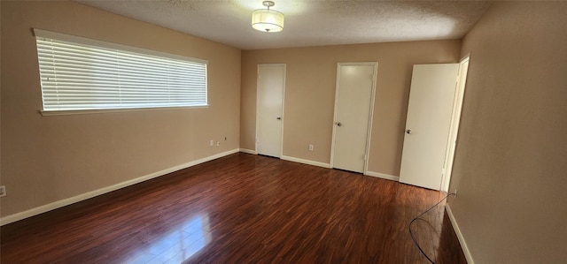 unfurnished bedroom with a textured ceiling and dark hardwood / wood-style flooring