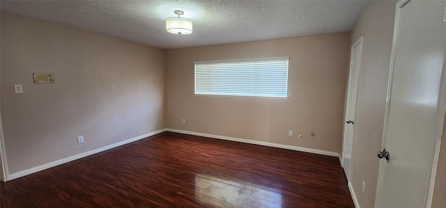 unfurnished room featuring dark wood-type flooring and a textured ceiling