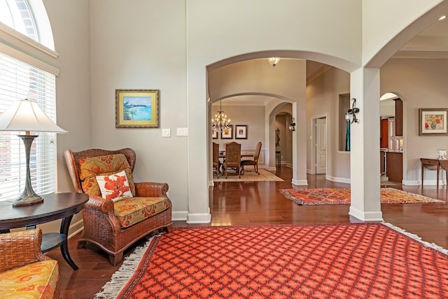 sitting room featuring a notable chandelier, dark hardwood / wood-style flooring, crown molding, and a towering ceiling