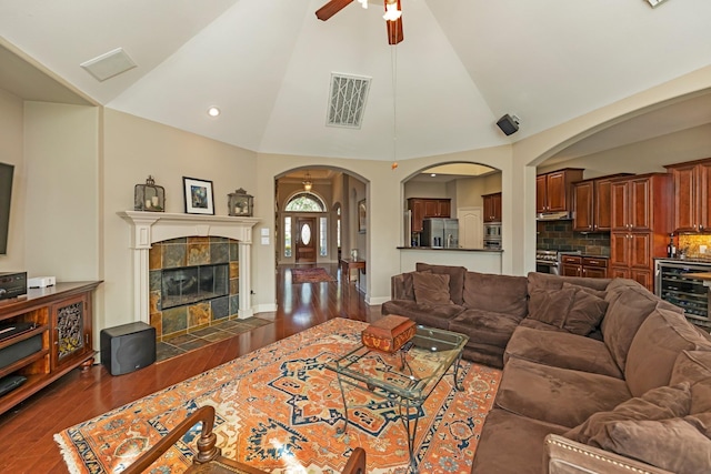 living room featuring ceiling fan, dark hardwood / wood-style floors, lofted ceiling, a fireplace, and wine cooler