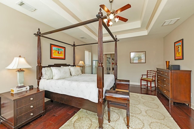 bedroom featuring ceiling fan, dark hardwood / wood-style flooring, and a tray ceiling