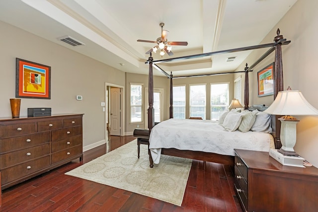 bedroom with ceiling fan, a tray ceiling, and dark hardwood / wood-style floors