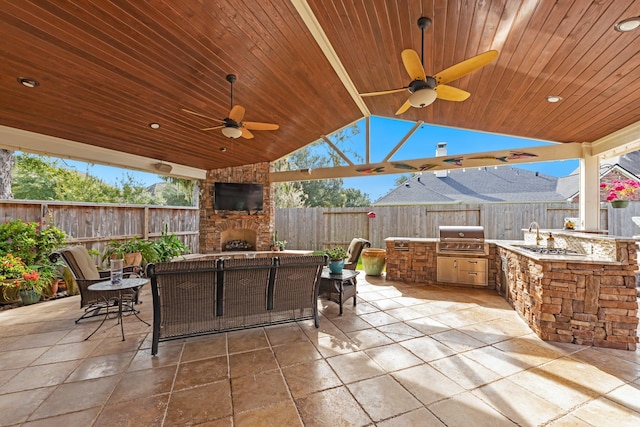 view of patio with ceiling fan, exterior kitchen, grilling area, and an outdoor stone fireplace