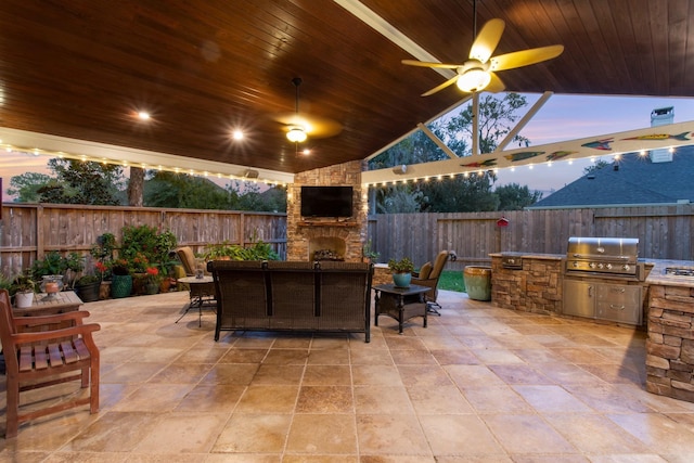 view of patio / terrace featuring area for grilling, ceiling fan, and an outdoor stone fireplace