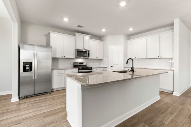 kitchen with appliances with stainless steel finishes, an island with sink, white cabinetry, and sink