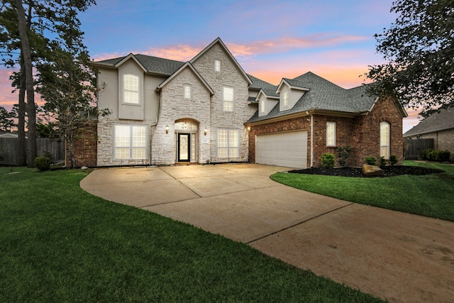 french provincial home featuring a front yard, concrete driveway, fence, and a garage