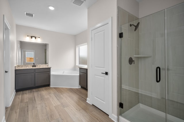 bathroom featuring hardwood / wood-style floors, vanity, and shower with separate bathtub