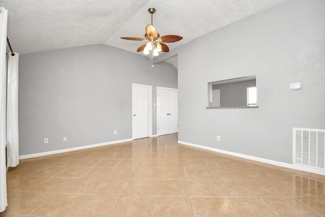 tiled spare room featuring lofted ceiling, ceiling fan, and a textured ceiling