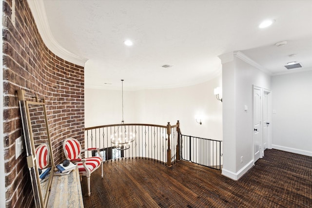 corridor featuring brick wall, wood-type flooring, ornamental molding, and a notable chandelier