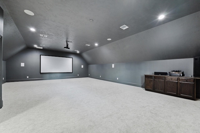 carpeted cinema room with vaulted ceiling