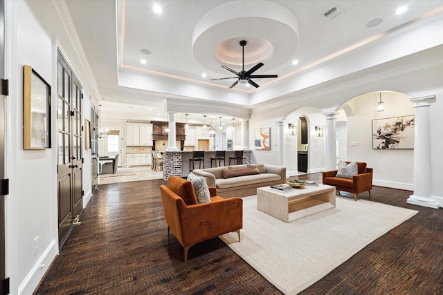 living room featuring ceiling fan, ornate columns, and a tray ceiling