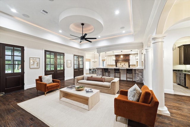 living room featuring ceiling fan, a tray ceiling, dark hardwood / wood-style flooring, french doors, and ornamental molding