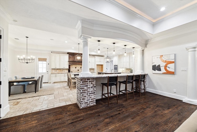 kitchen featuring pendant lighting, an inviting chandelier, decorative backsplash, kitchen peninsula, and a breakfast bar area