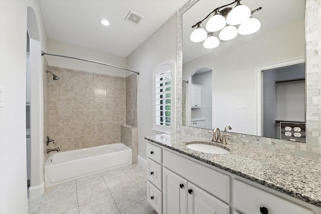 bathroom with tiled shower / bath combo, tile patterned floors, tasteful backsplash, and vanity