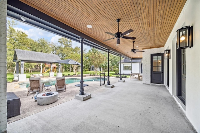 view of patio featuring ceiling fan, a gazebo, and a fire pit