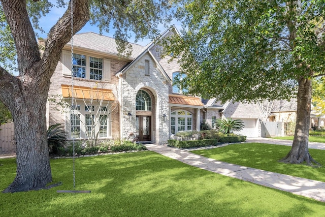 view of front of house with a garage, stone siding, brick siding, and a front yard