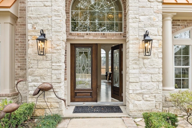 view of exterior entry featuring stone siding and brick siding