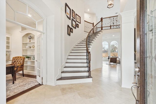 entrance foyer featuring light tile patterned flooring, a towering ceiling, and french doors