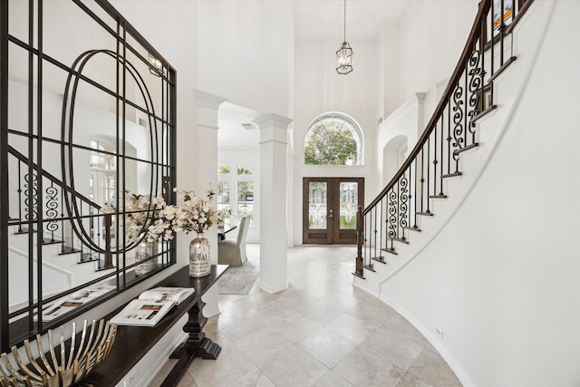 foyer entrance with french doors, ornate columns, stairway, a high ceiling, and baseboards