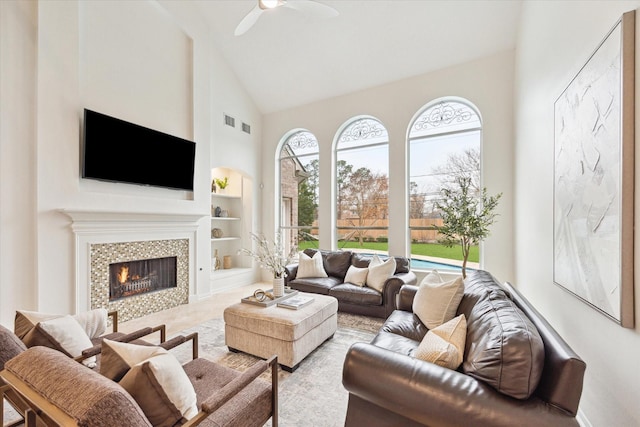 living room with ceiling fan, high vaulted ceiling, and a fireplace