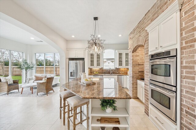 kitchen featuring sink, a center island, hanging light fixtures, appliances with stainless steel finishes, and white cabinets