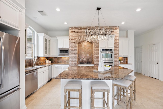 kitchen featuring visible vents, decorative backsplash, appliances with stainless steel finishes, a fireplace, and a sink