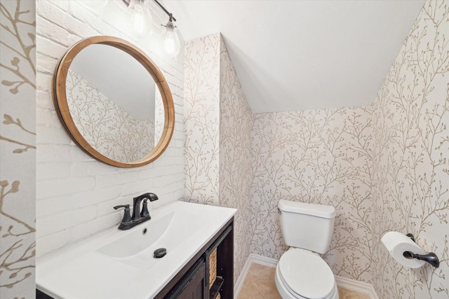 half bath with tile patterned flooring, vanity, toilet, and wallpapered walls