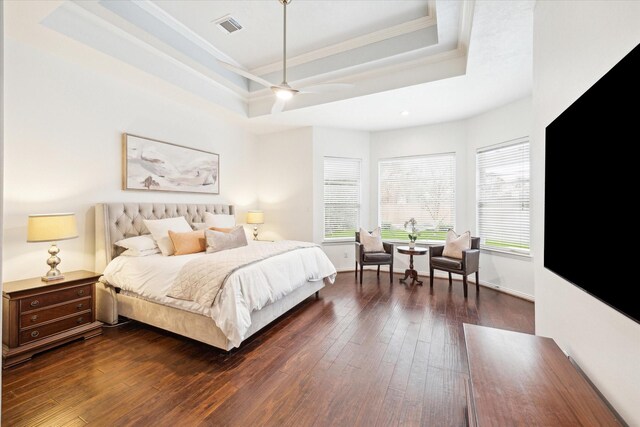 bedroom with a raised ceiling, ornamental molding, and dark wood-type flooring