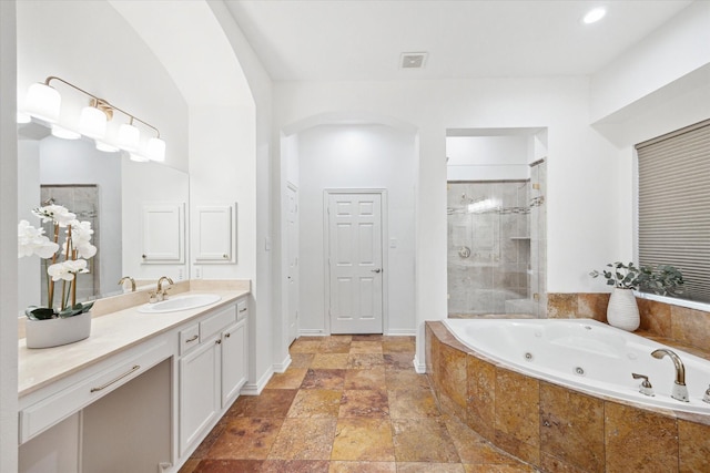 bathroom featuring stone tile floors, vanity, visible vents, a shower stall, and a whirlpool tub